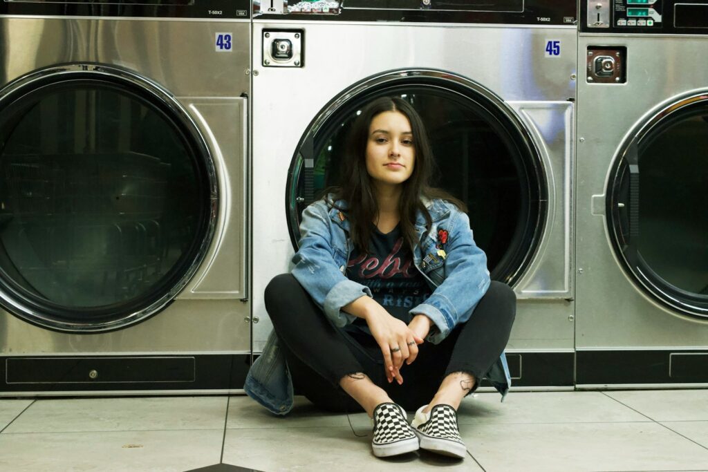 woman in blue denim jacket sitting on front load washing machine