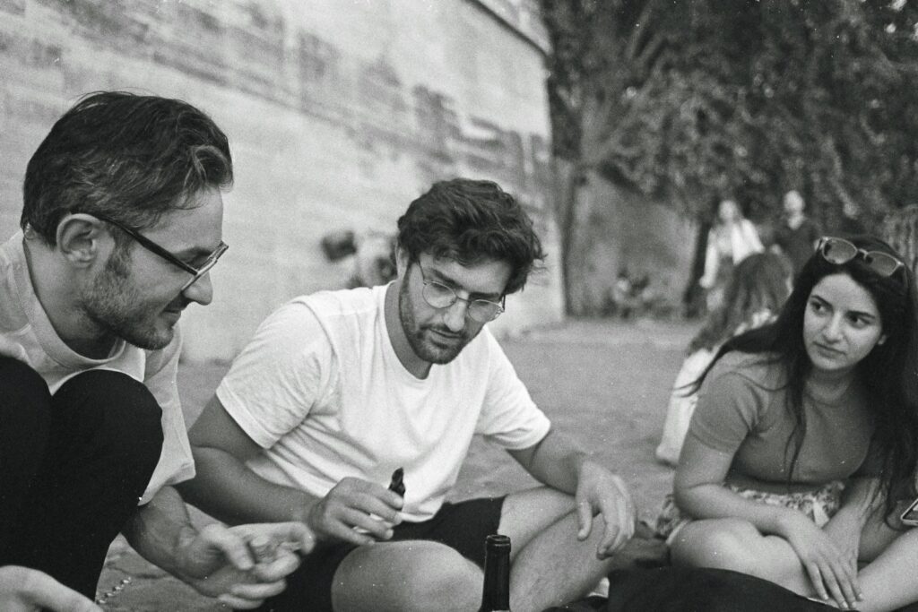 a group of people sitting on the ground looking at a cell phone