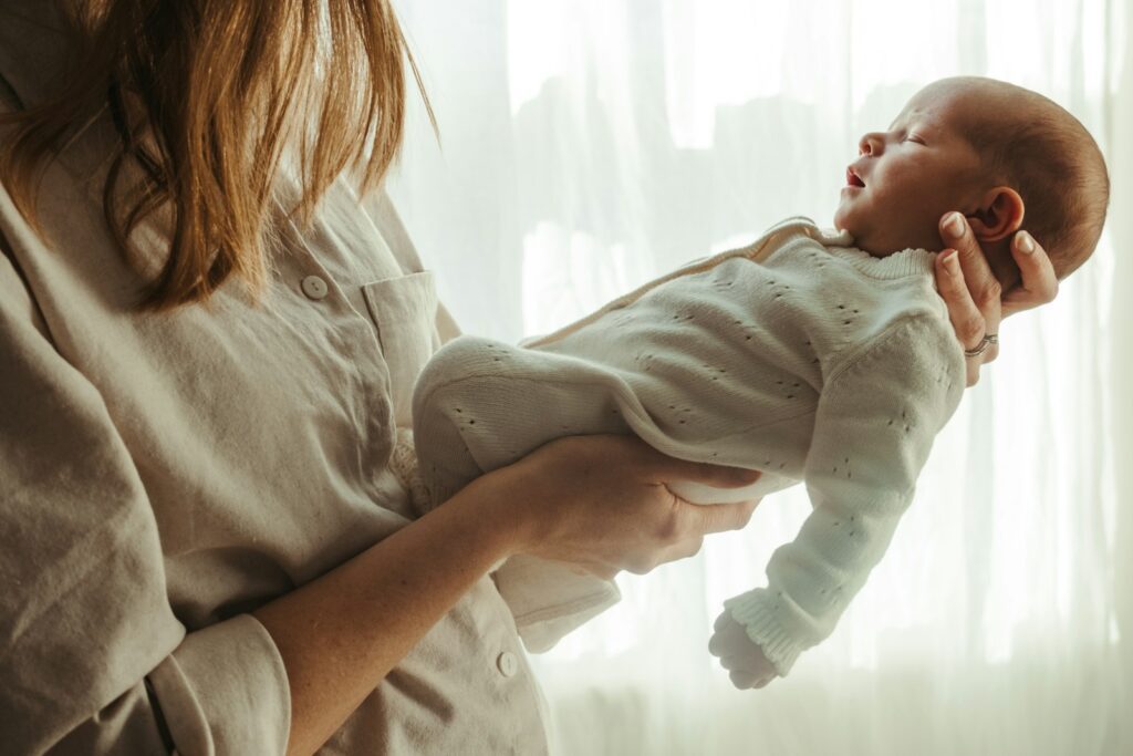 Mother holding her newborn baby near a window