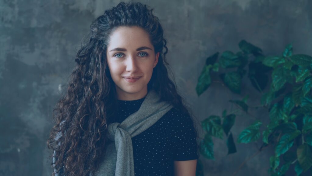 A woman with curly hair smiles at the camera.