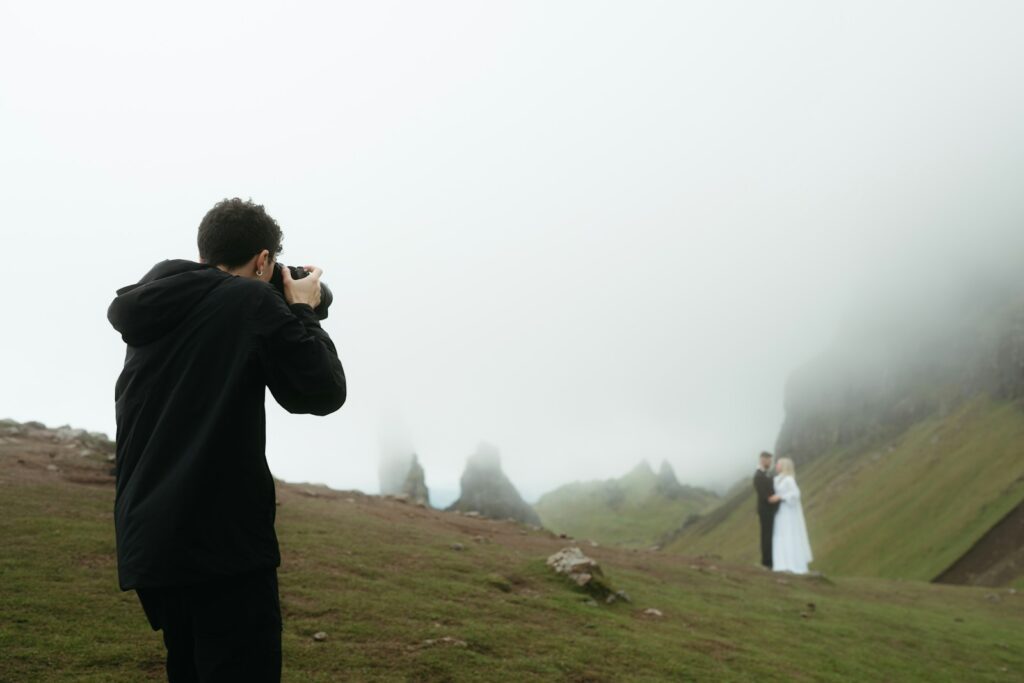 Photographer takes picture of couple in foggy landscape.