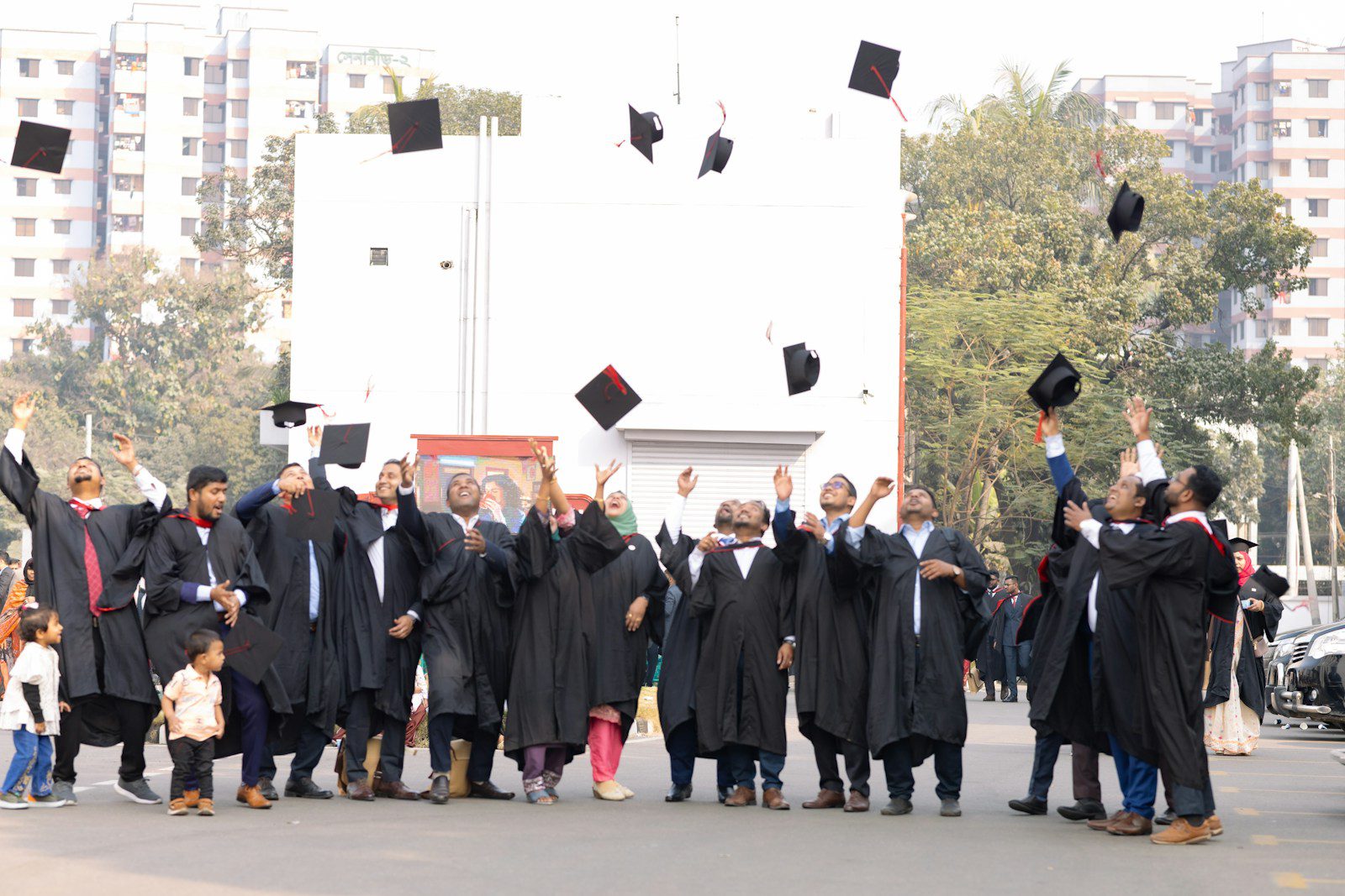 Graduates in caps and gowns toss hats in the air.
