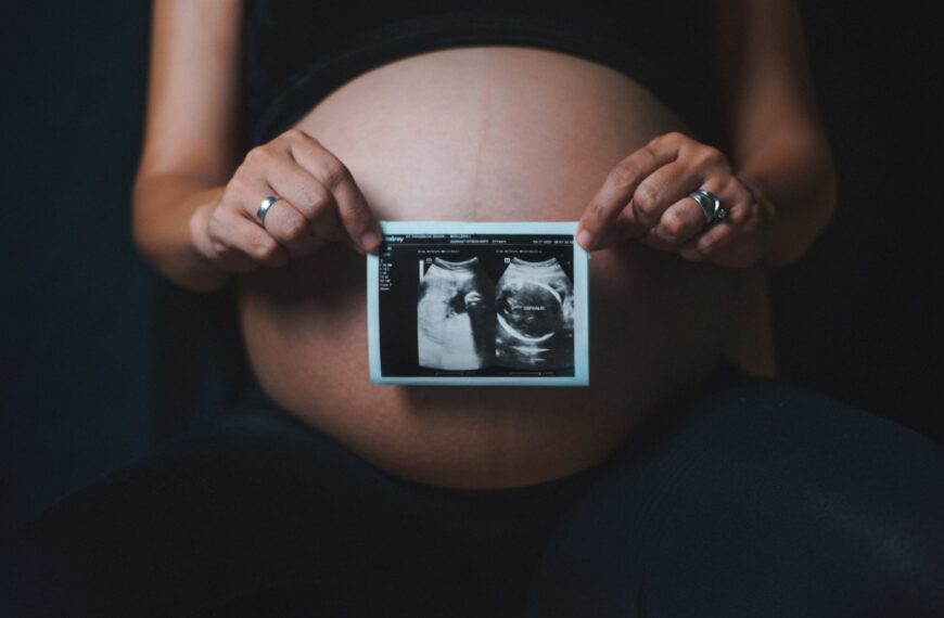 a pregnant woman holding a camera in her hands