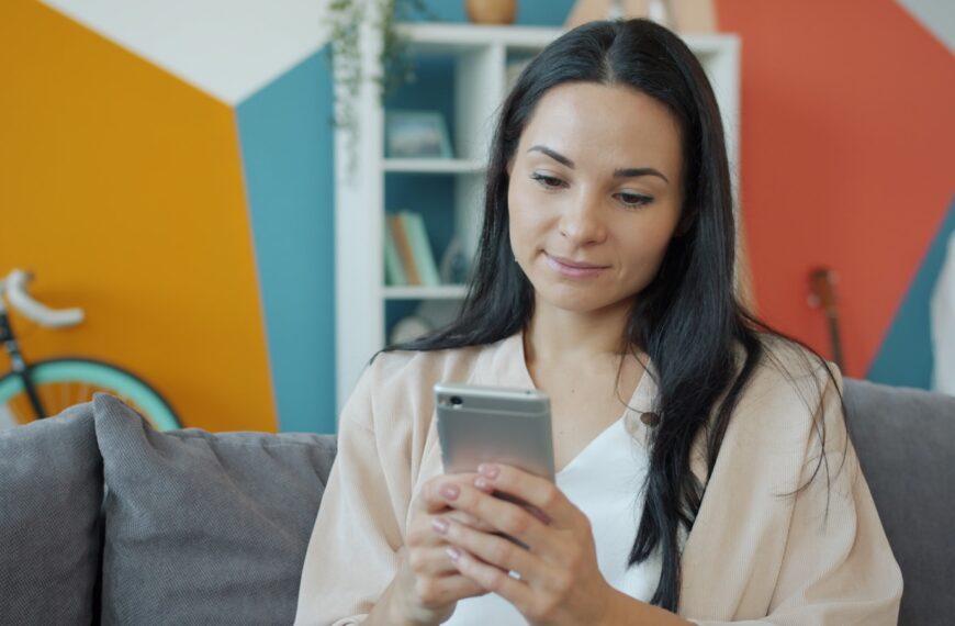 A woman looking at her smartphone on a couch.