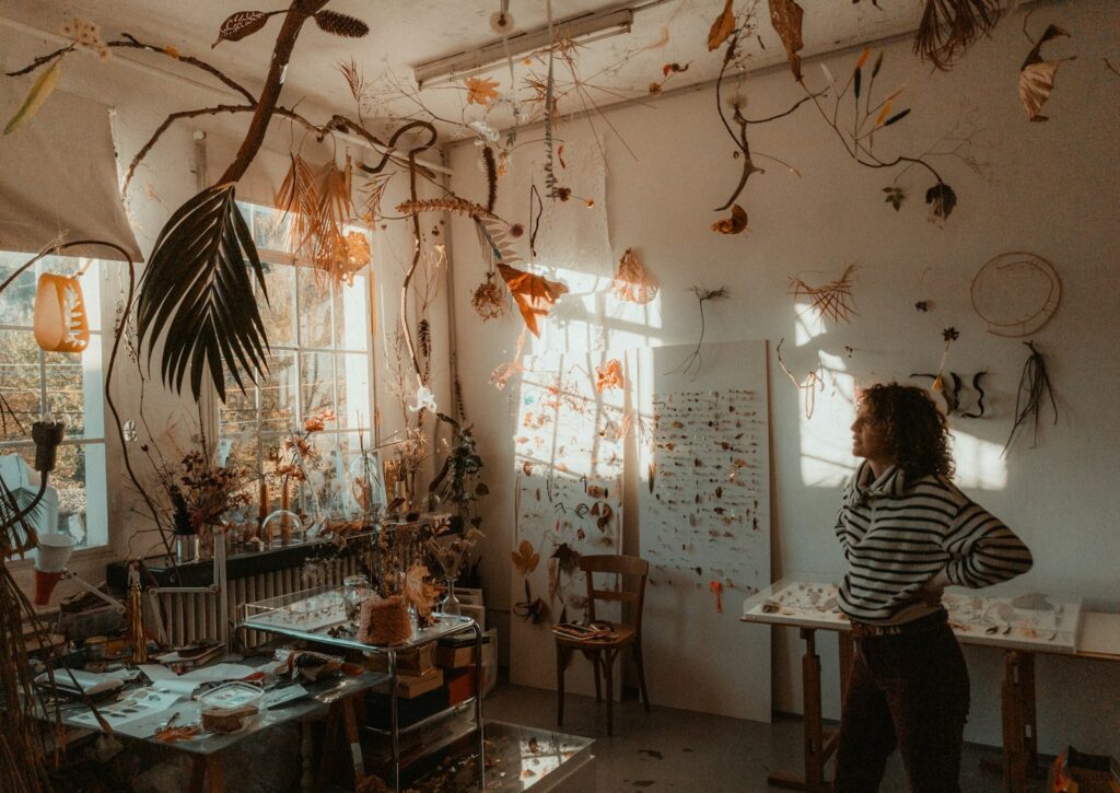 a woman standing in a room with a lot of plants hanging from the ceiling