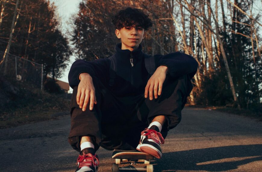 man in black jacket and black pants sitting on road during daytime