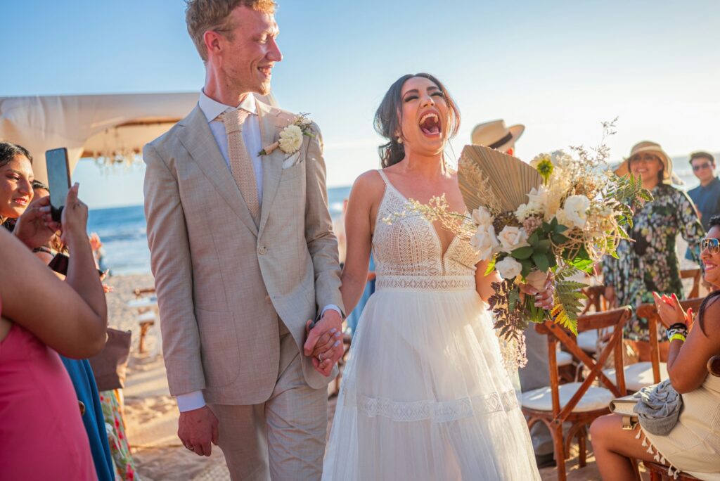Newlyweds celebrating on a sunny beach wedding day.