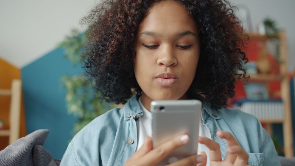 Young woman looking at smartphone screen of smartphone.