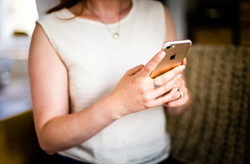 shallow focus photo of person in white sleeveless shirt holding gold iPhone 7