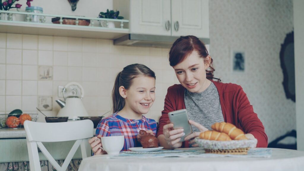 A mother and daughter share a phone together.