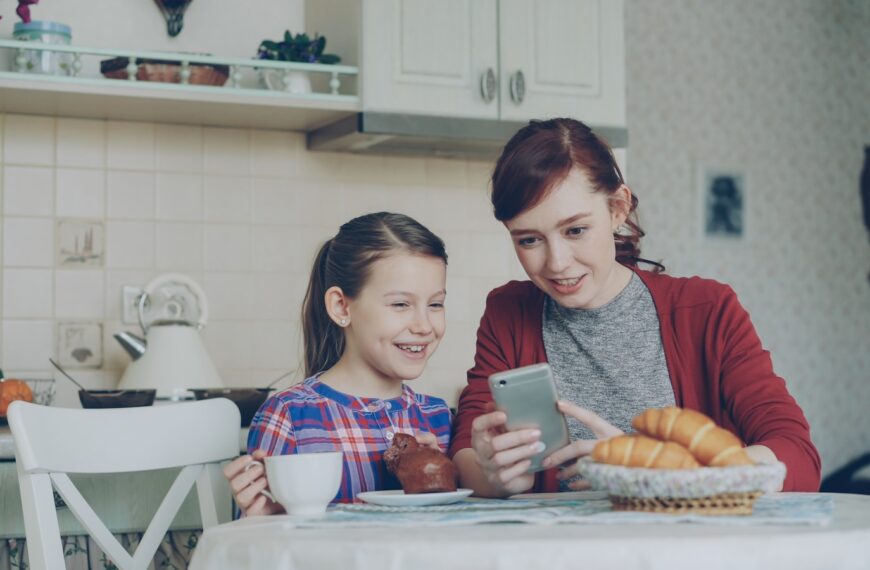 A mother and daughter share a phone together.