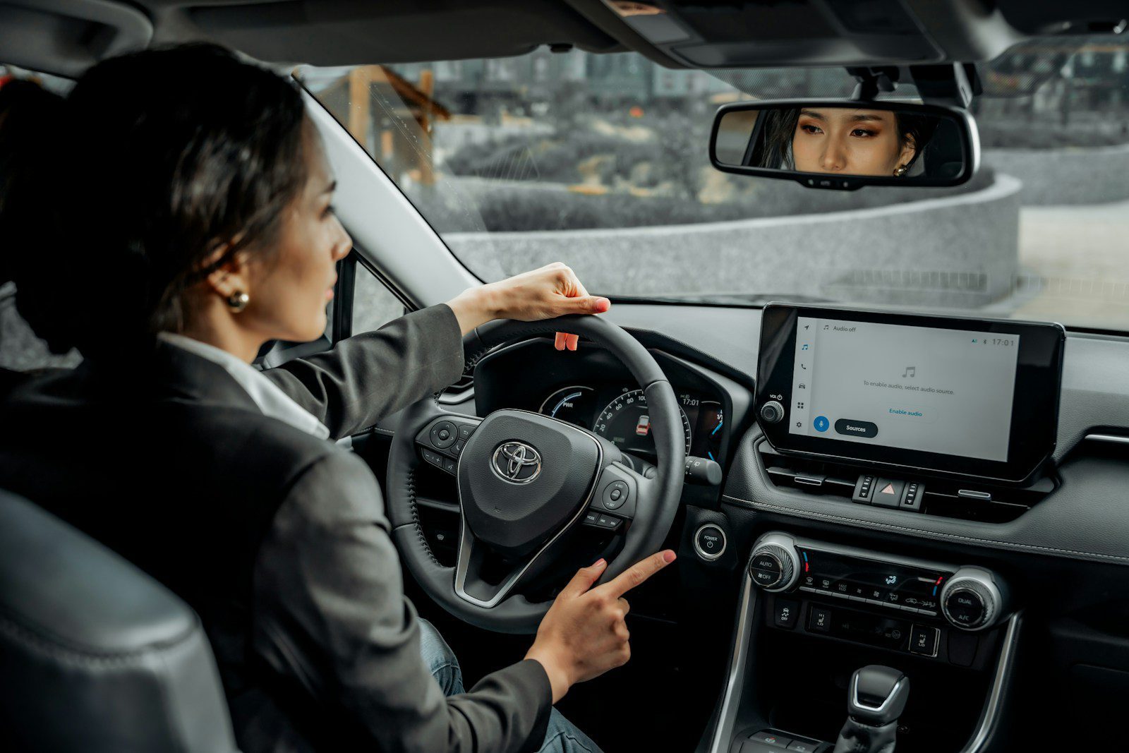A woman driving a car with a man in the back seat