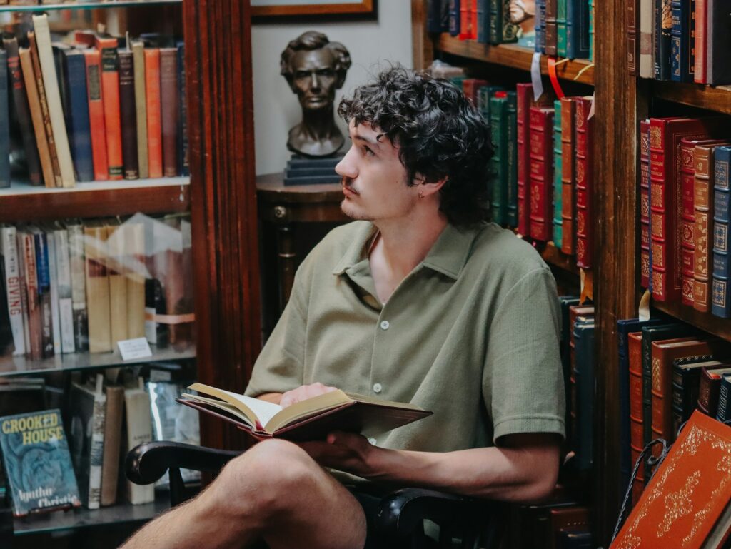 Man reads in a cozy bookstore surrounded by books.