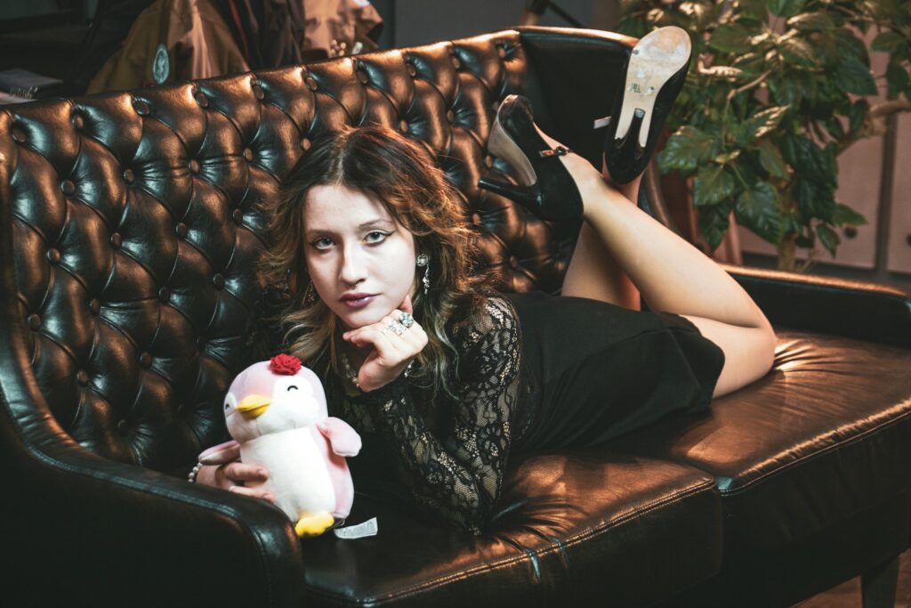 A woman poses with a plushie on a couch.