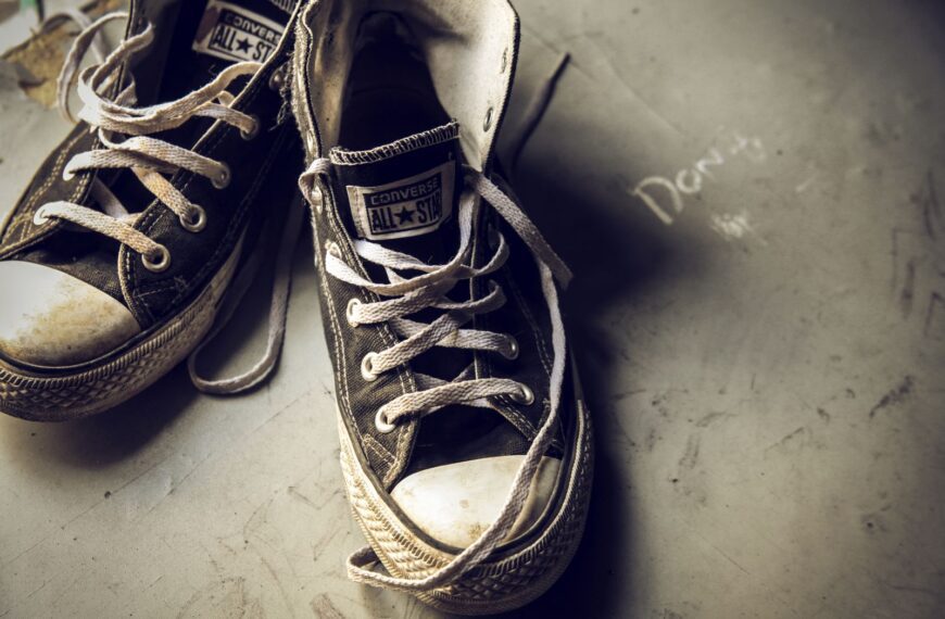 Close-up of worn Converse All Star sneakers, capturing a vintage and retro vibe on a muted background.