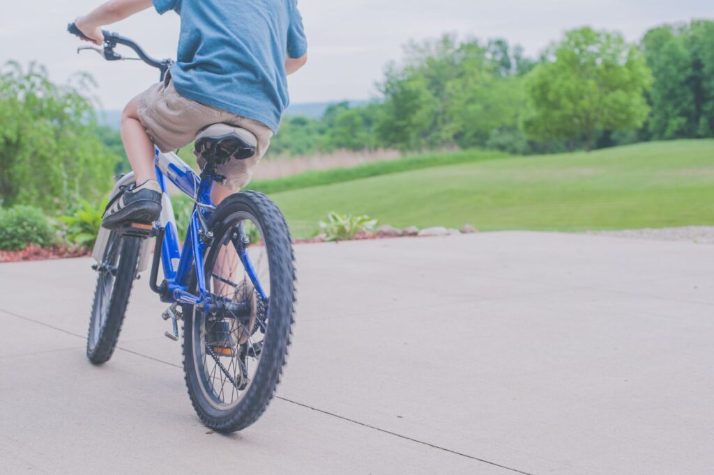 A young boy enjoying a ride on a blue bicycle in a lush outdoor setting.