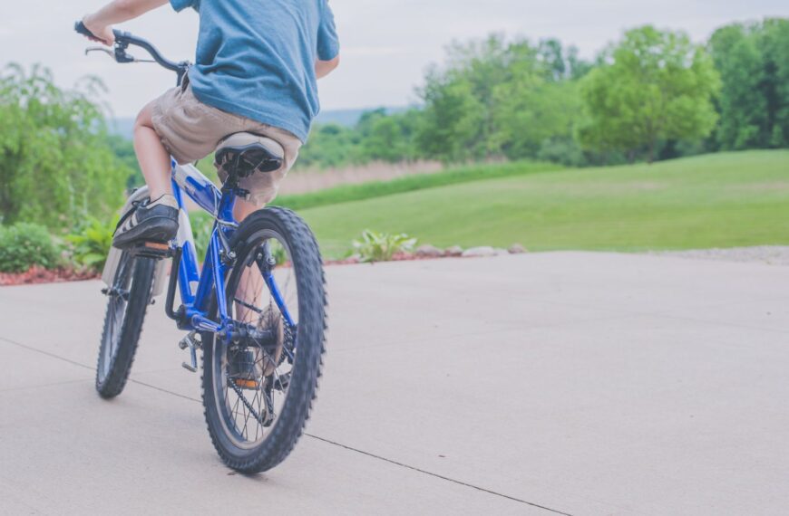 A young boy enjoying a ride on a blue bicycle in a lush outdoor setting.