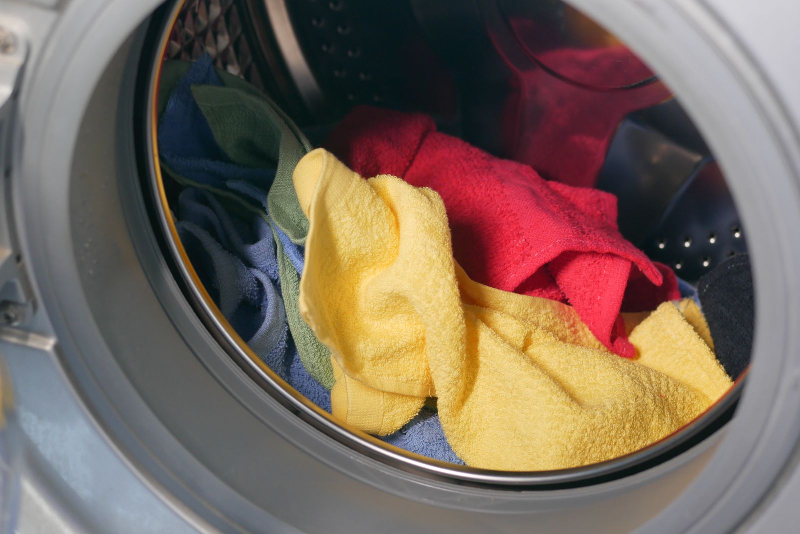 Vibrant close-up of multicolored towels inside a washing machine, ready for a wash.