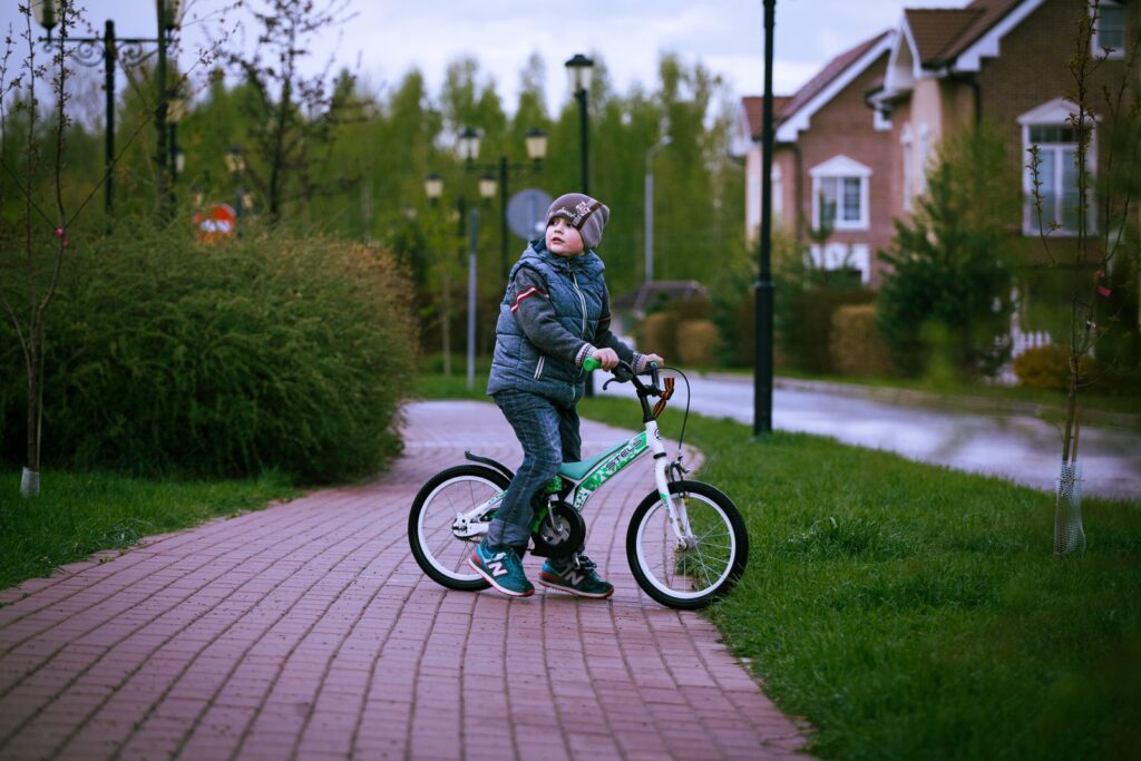 A young boy on a bicycle in a suburban neighborhood on a cool day.