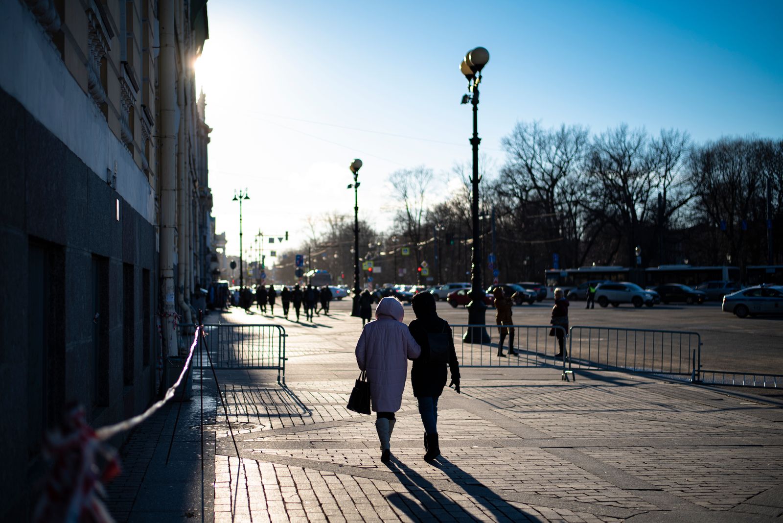 Silhouetted pedestrians walking on a city street at dusk, capturing urban life.