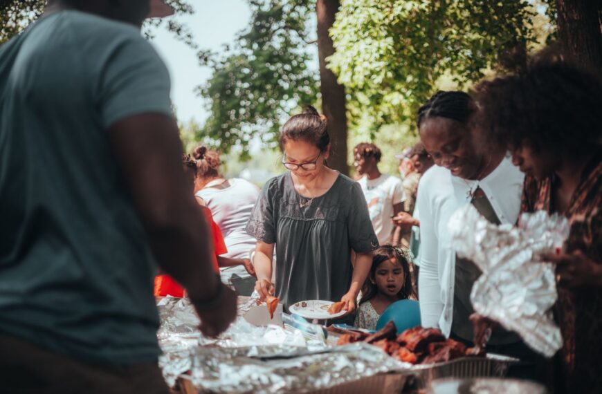 A lively barbecue gathering with diverse group outdoors enjoying food and summer weather.