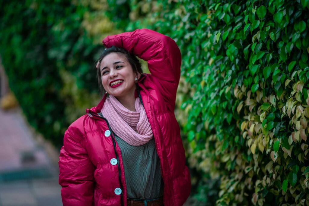 Cheerful woman in a pink winter jacket expressing joy outdoors.