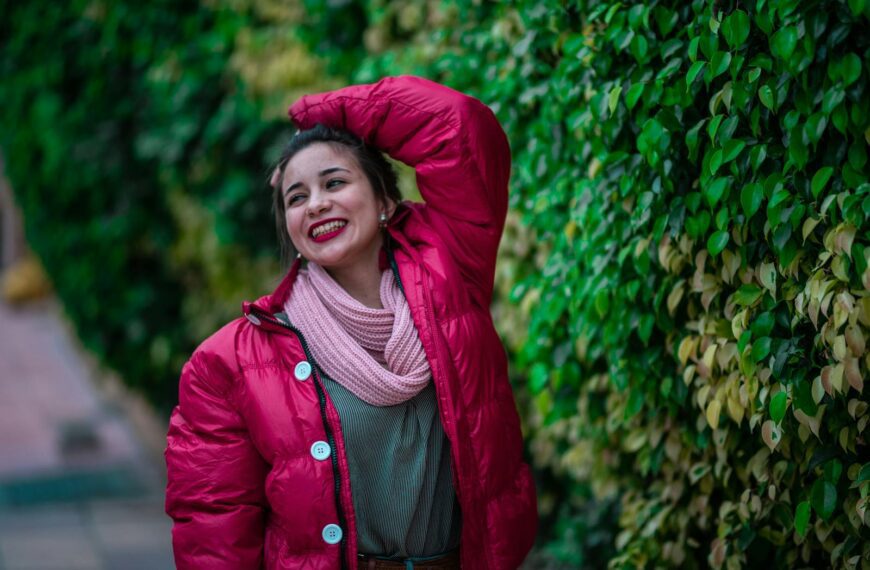 Cheerful woman in a pink winter jacket expressing joy outdoors.