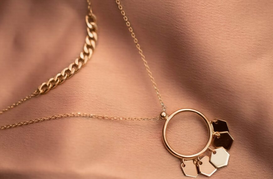 Close-up of a stylish gold necklace with hexagonal charms on textured fabric, showcasing elegance.