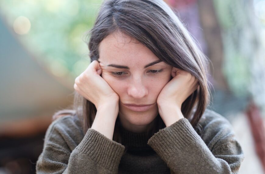Portrait of a young woman looking pensive and thoughtful while sitting outdoors.