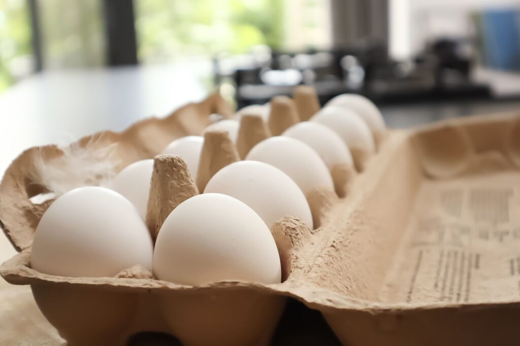 Fresh white eggs in a cardboard carton on a kitchen counter.