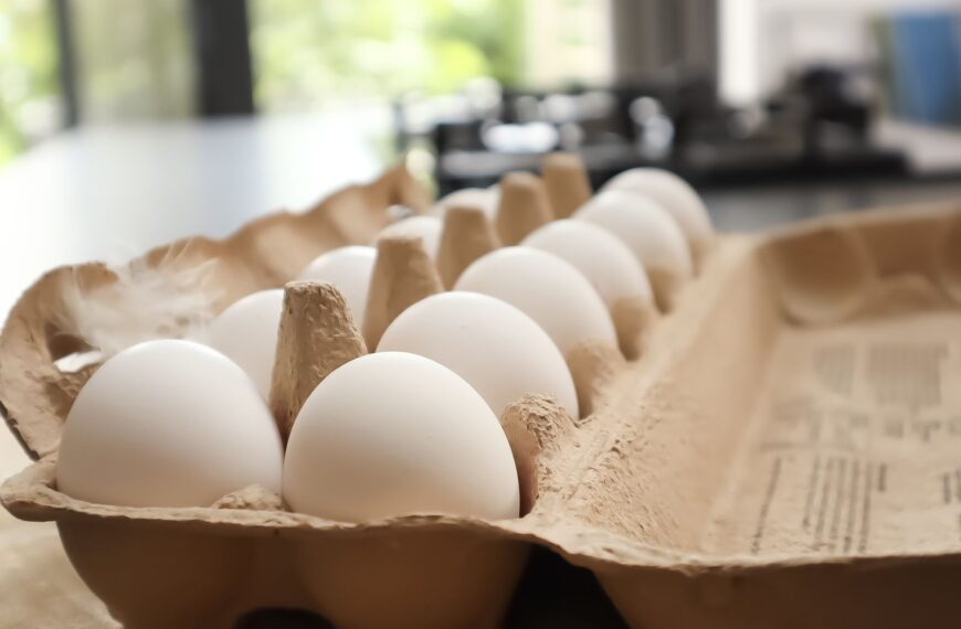 Fresh white eggs in a cardboard carton on a kitchen counter.