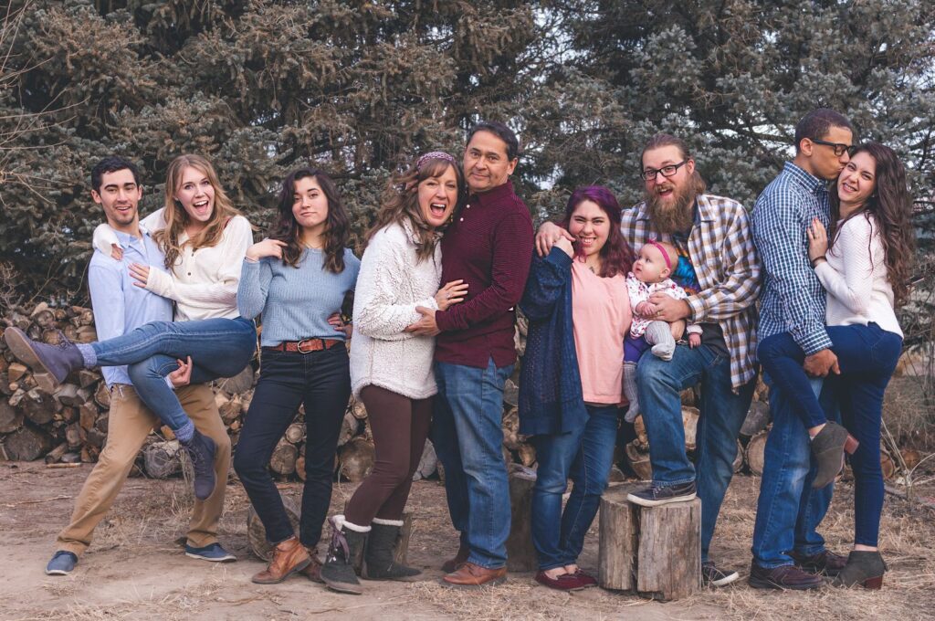 A joyful family poses together outdoors during a fall day, expressing love and happiness.