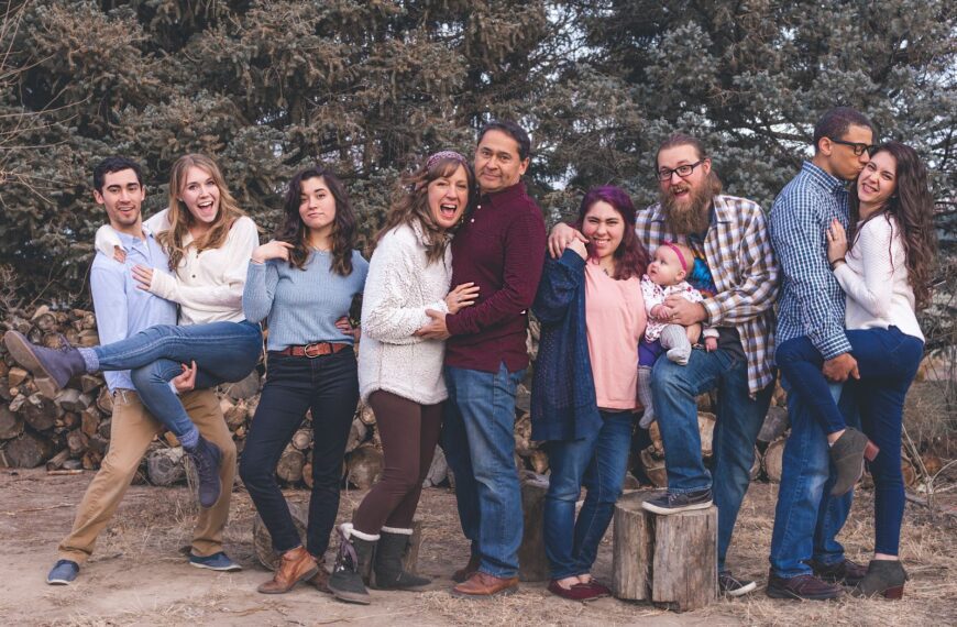 A joyful family poses together outdoors during a fall day, expressing love and happiness.