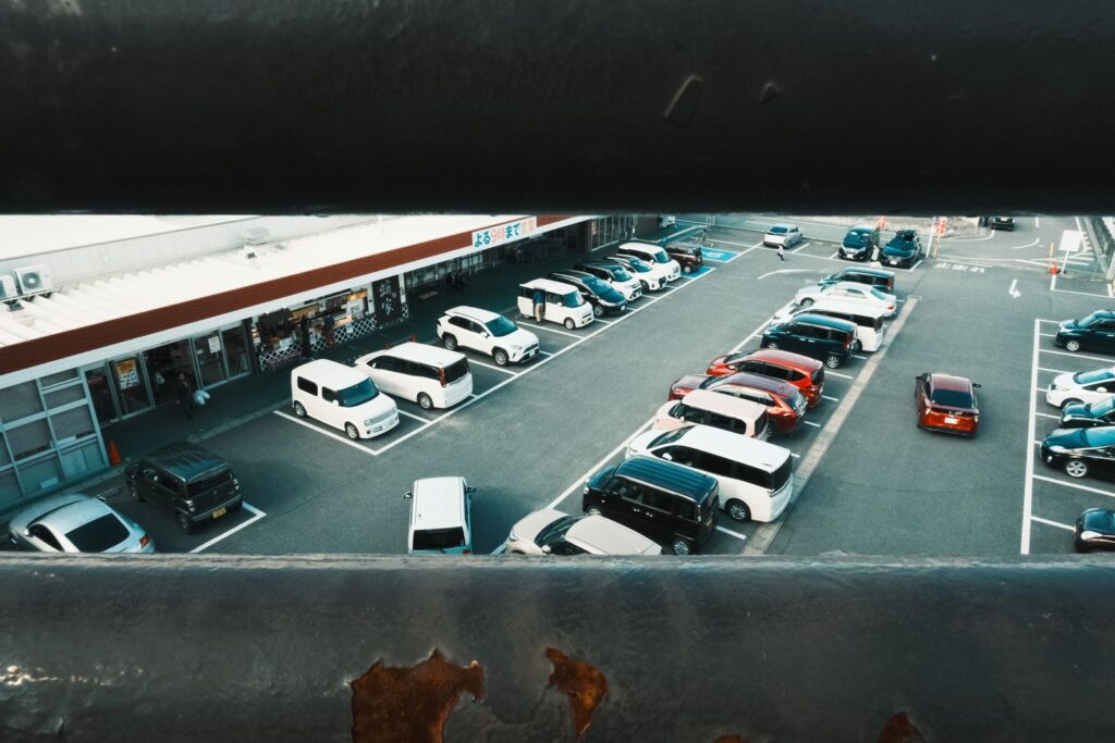 Aerial view of a busy parking lot in Toyota, Japan, showcasing cars and shops.
