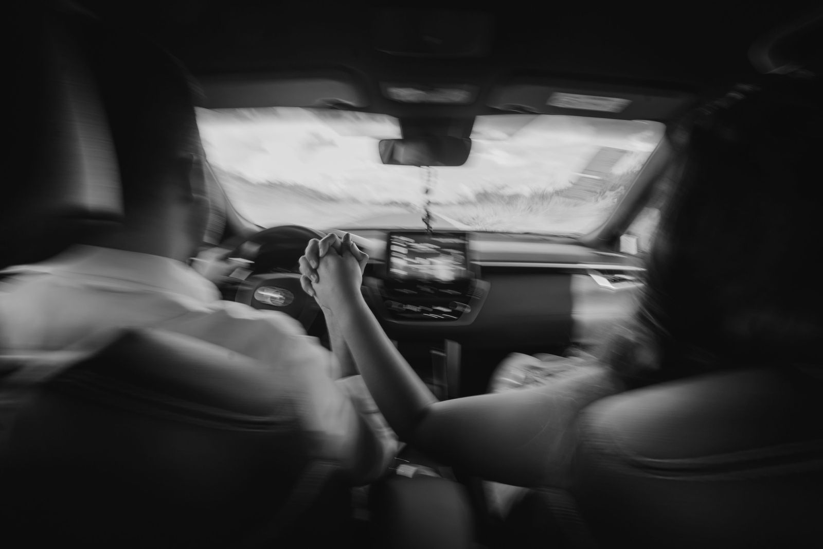 A couple holding hands while driving through the scenic roads of Brazil in a monochrome setting.