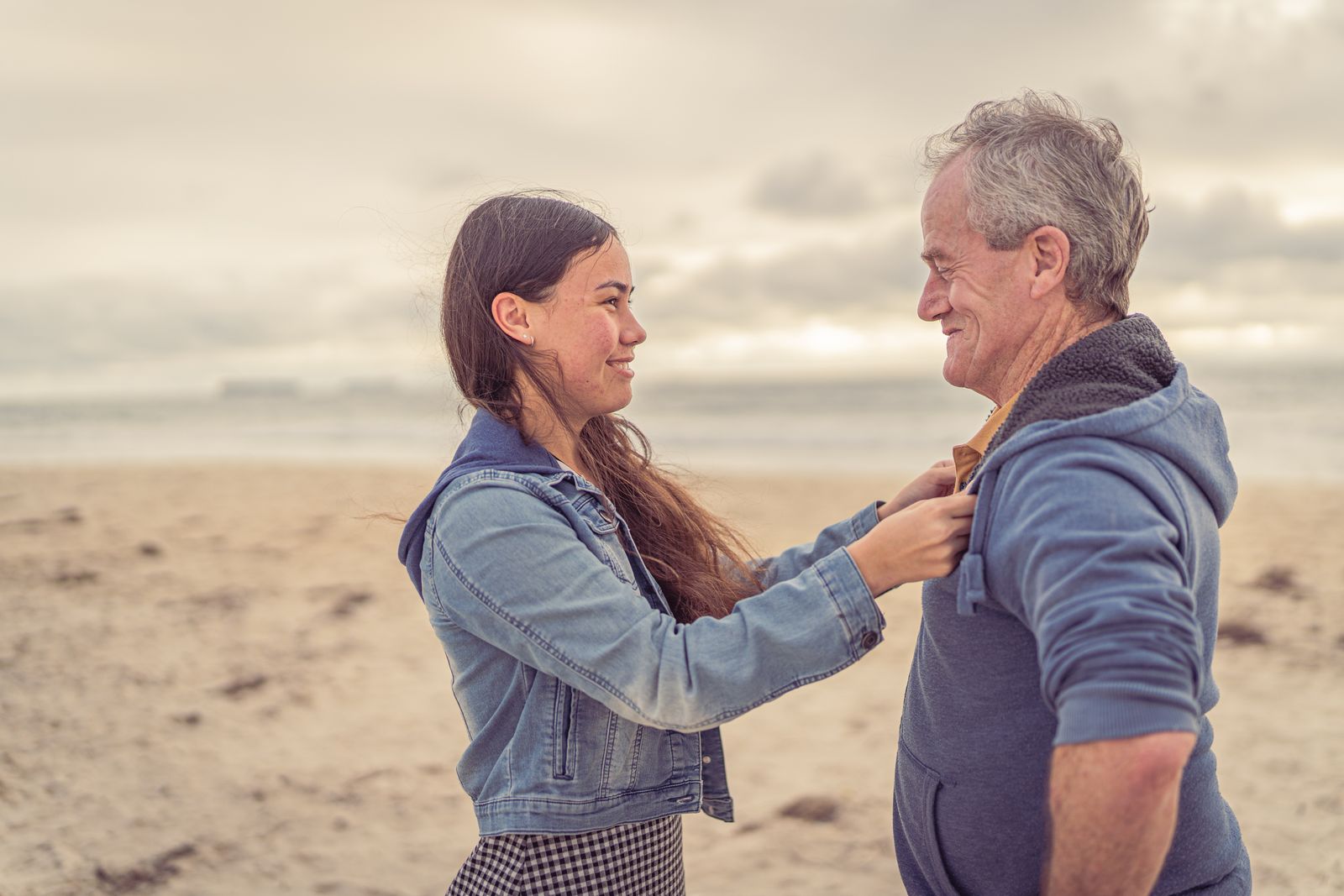 A father and daughter share a joyful moment at the beach, embracing family bonds.
