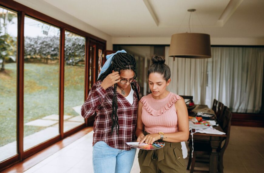 Two women reviewing color swatches in a bright living room, focusing on design options.