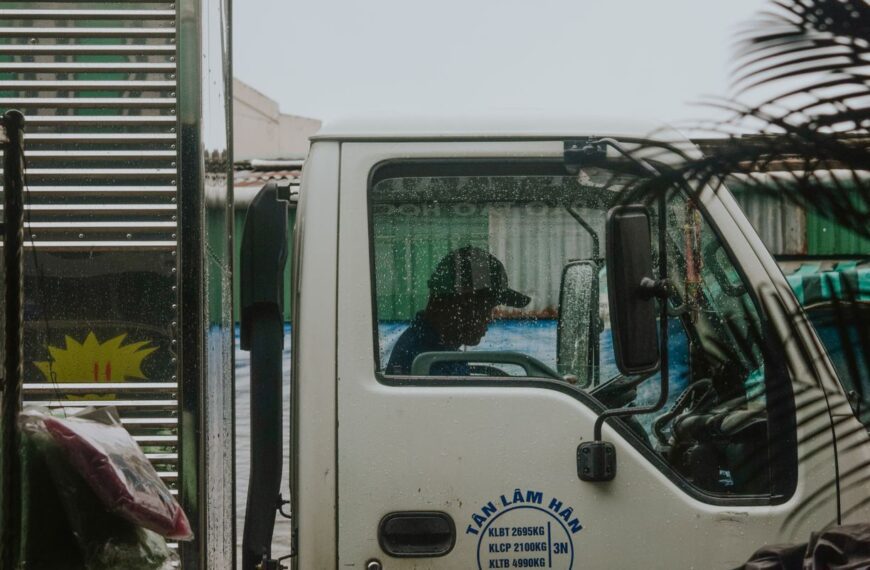 Side profile view of a truck driver inside cab during rain. Urban delivery concept.