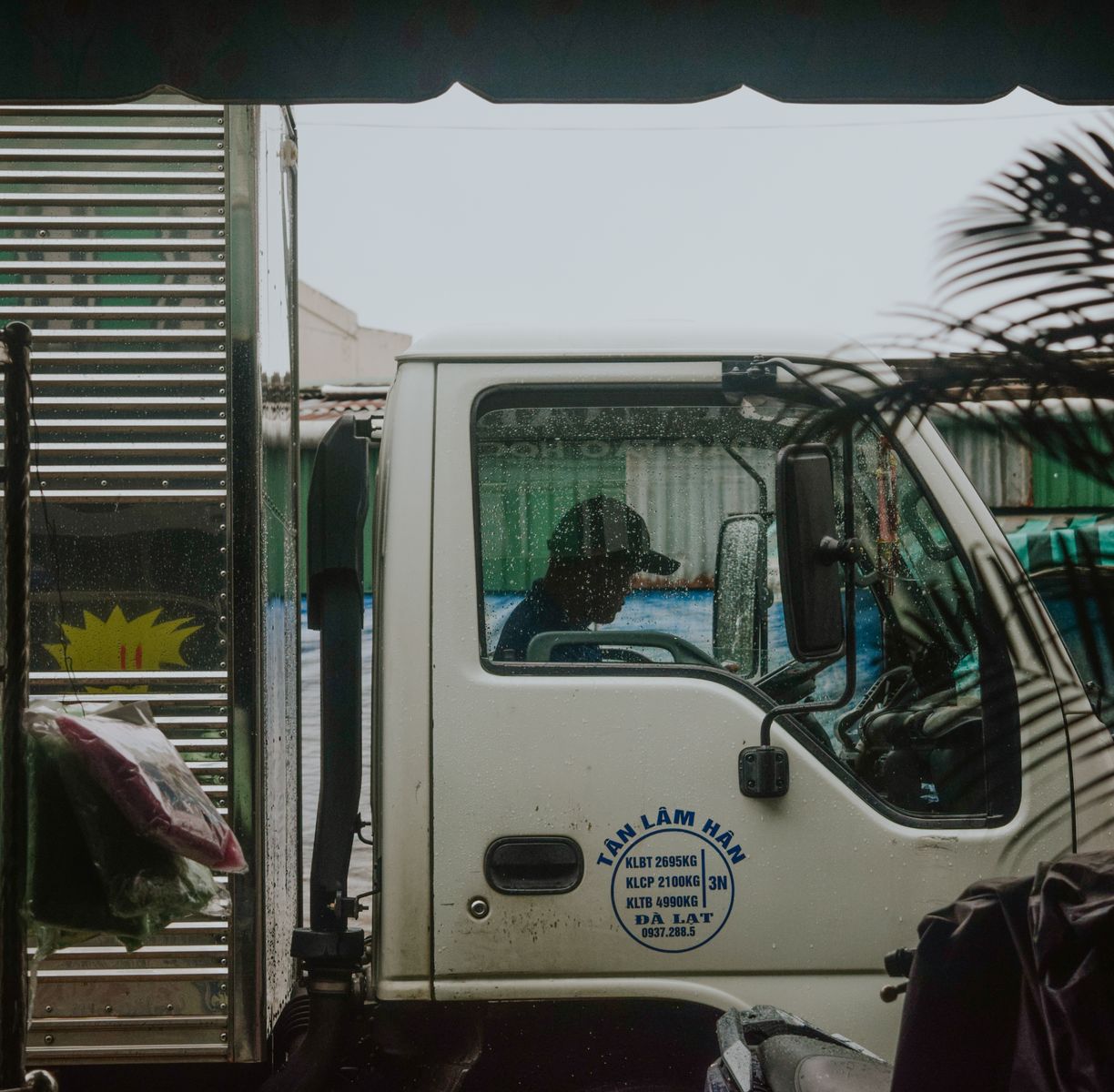 Side profile view of a truck driver inside cab during rain. Urban delivery concept.