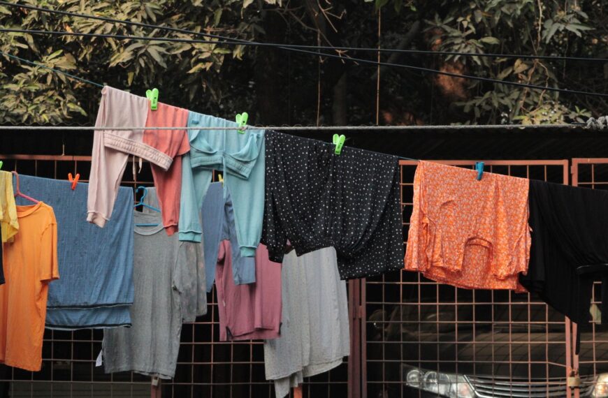 Vibrant clothes hanging outdoors on a clothesline in a backyard setting.