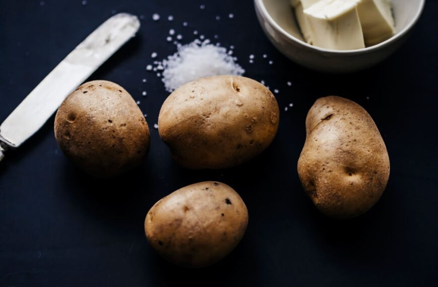Artistic still life showcasing potatoes, butter, and salt on a dark background.
