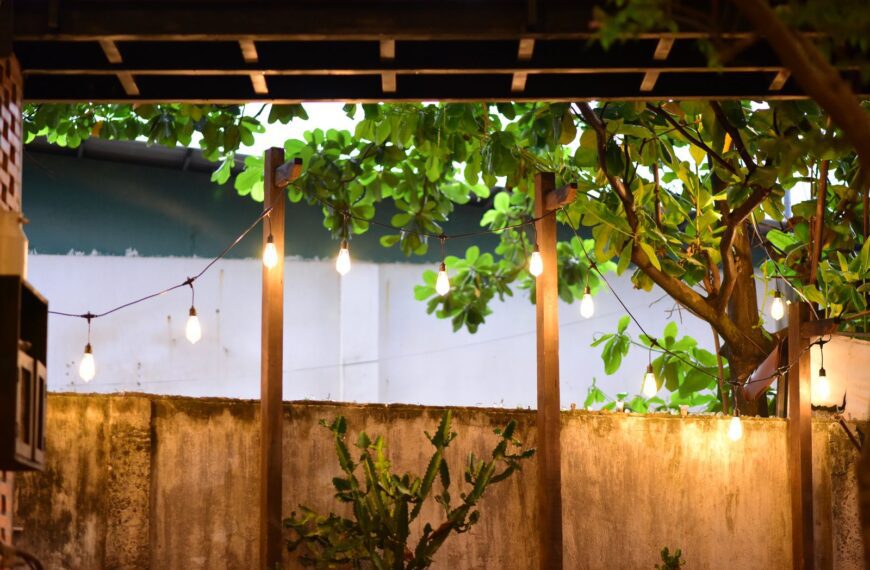 Warm string lights illuminate a backyard with lush foliage, creating a cozy outdoor ambiance.