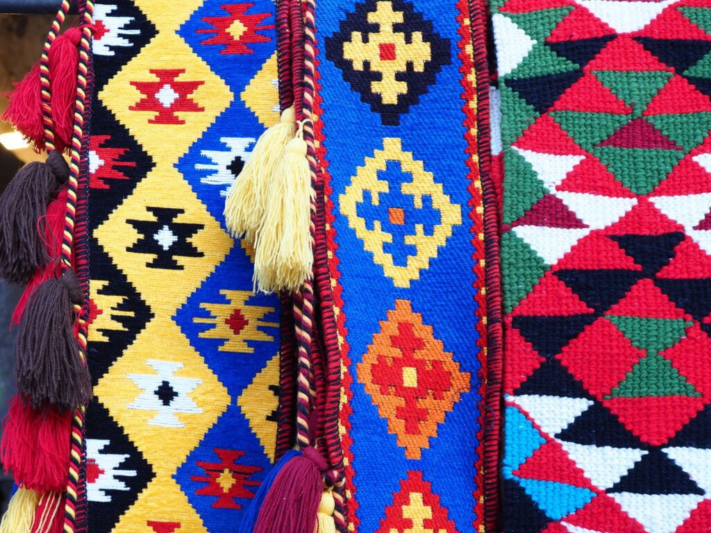 Vibrant handmade woven textiles featuring geometric patterns and colorful tassels, captured in Qatar.