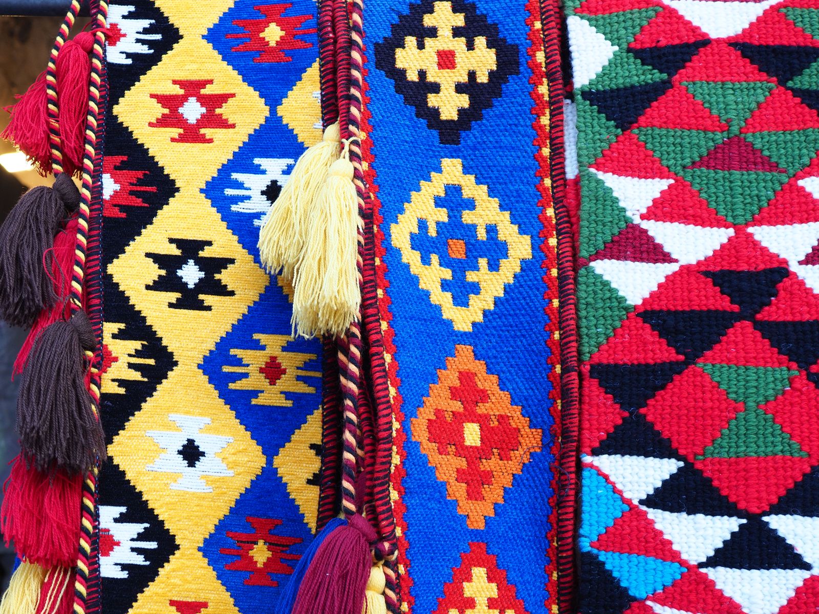 Vibrant handmade woven textiles featuring geometric patterns and colorful tassels, captured in Qatar.