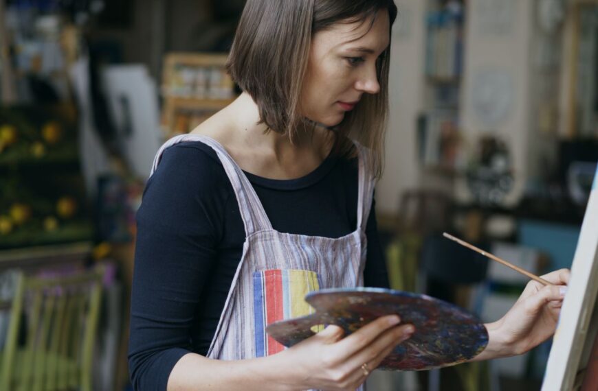 Focused female artist creating artwork on canvas indoors.