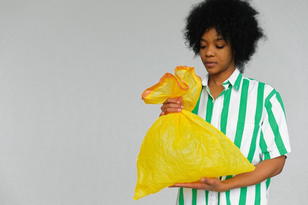 Woman with afro holding yellow recyclable bag, promoting eco-friendly lifestyle indoors.