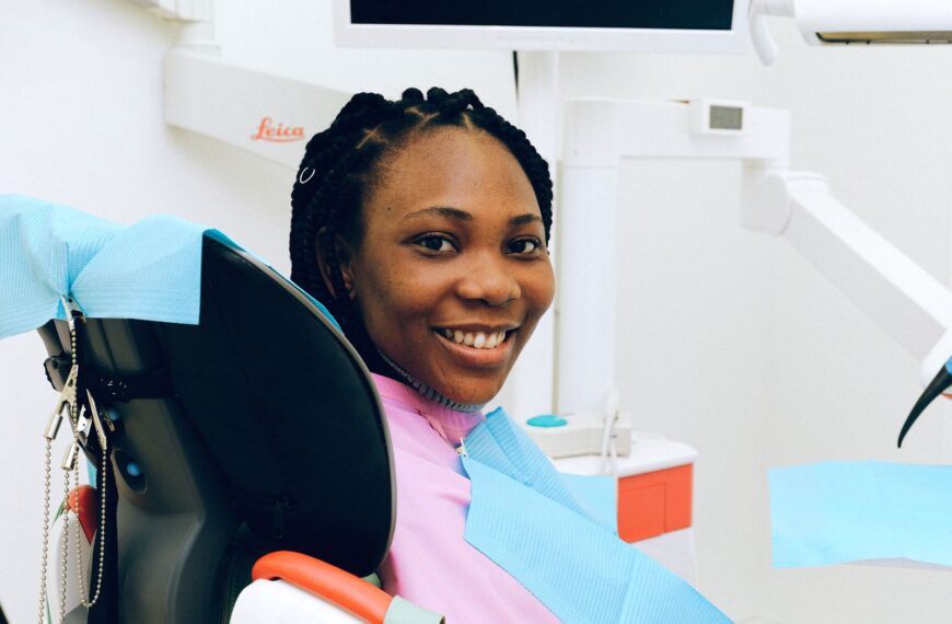 African American woman smiling while sitting in a dental clinic chair during a check-up.