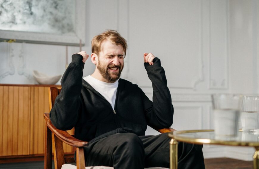 A bearded man expressing emotional distress in a modern interior setting, seeking mental health support.