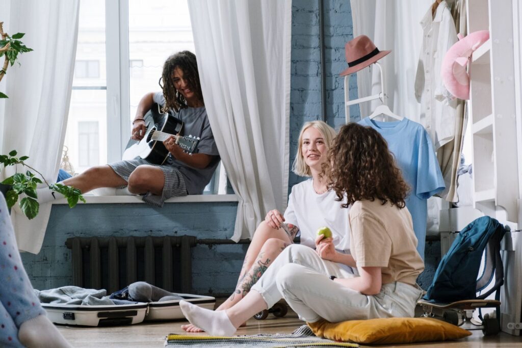 Cozy indoor scene with friends playing guitar and relaxing, capturing a sense of companionship.