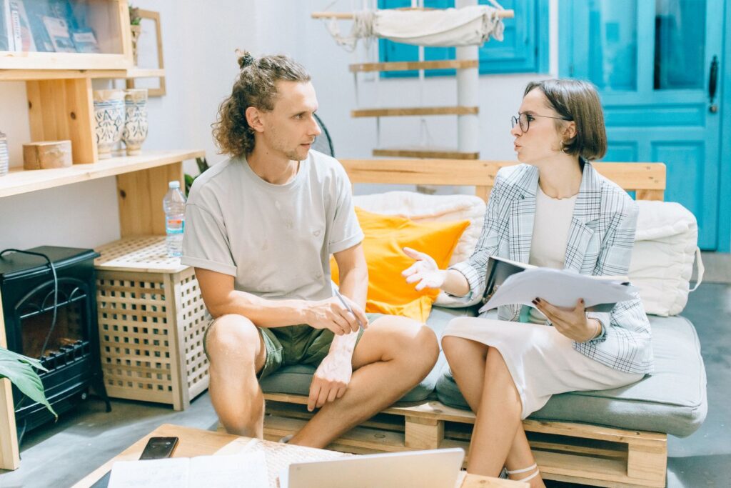 A man and woman discussing work in a stylish, bright living room setting.
